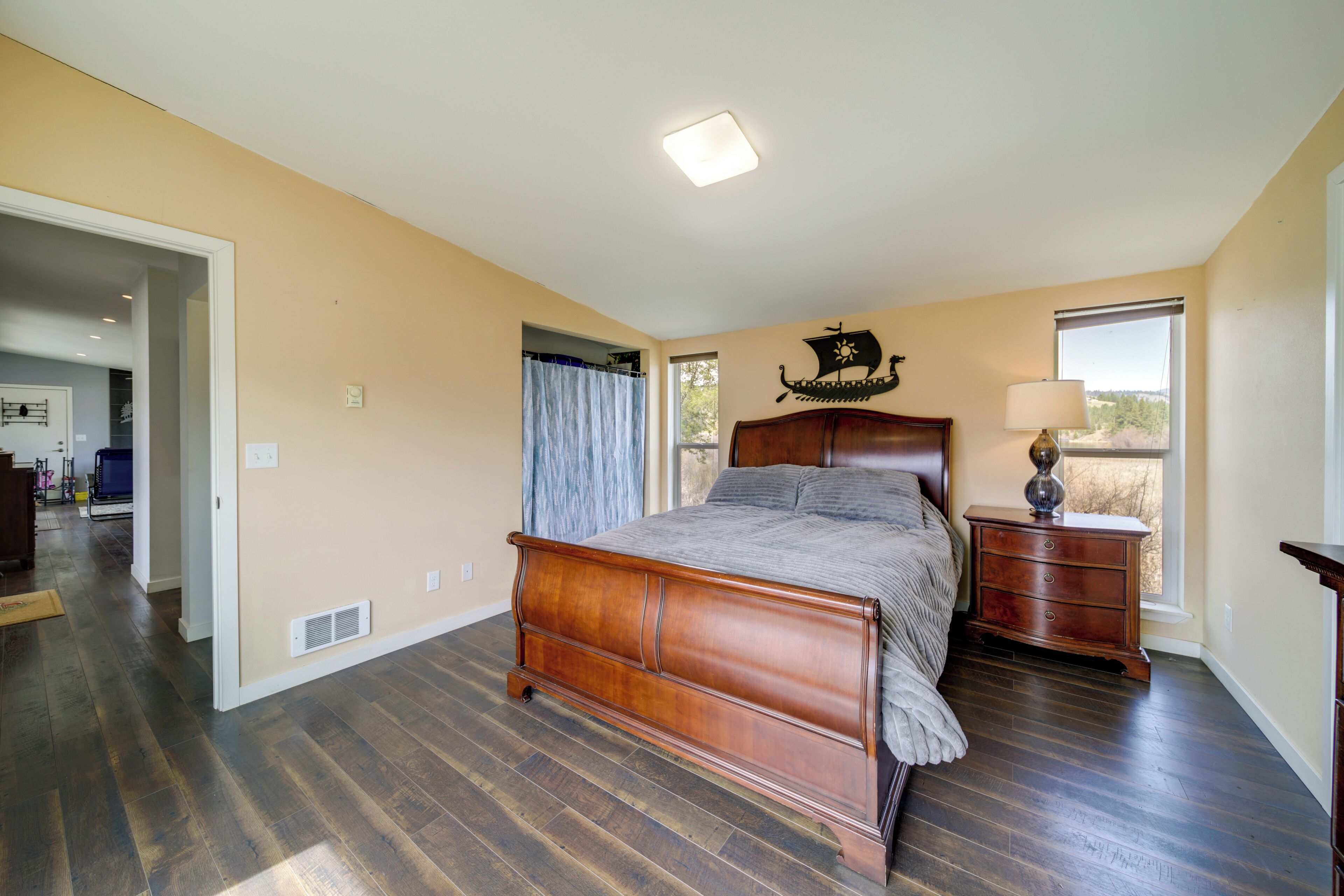 Une chambre à coucher avec un lit en bois, une table de chevet, une commode et une fenêtre donnant sur un beau paysage.