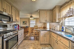 A kitchen with wooden cabinets, a stove, a microwave, and a sink. - Cozy Cody House <10 Mi to Buffalo Bill Center! (Cody)