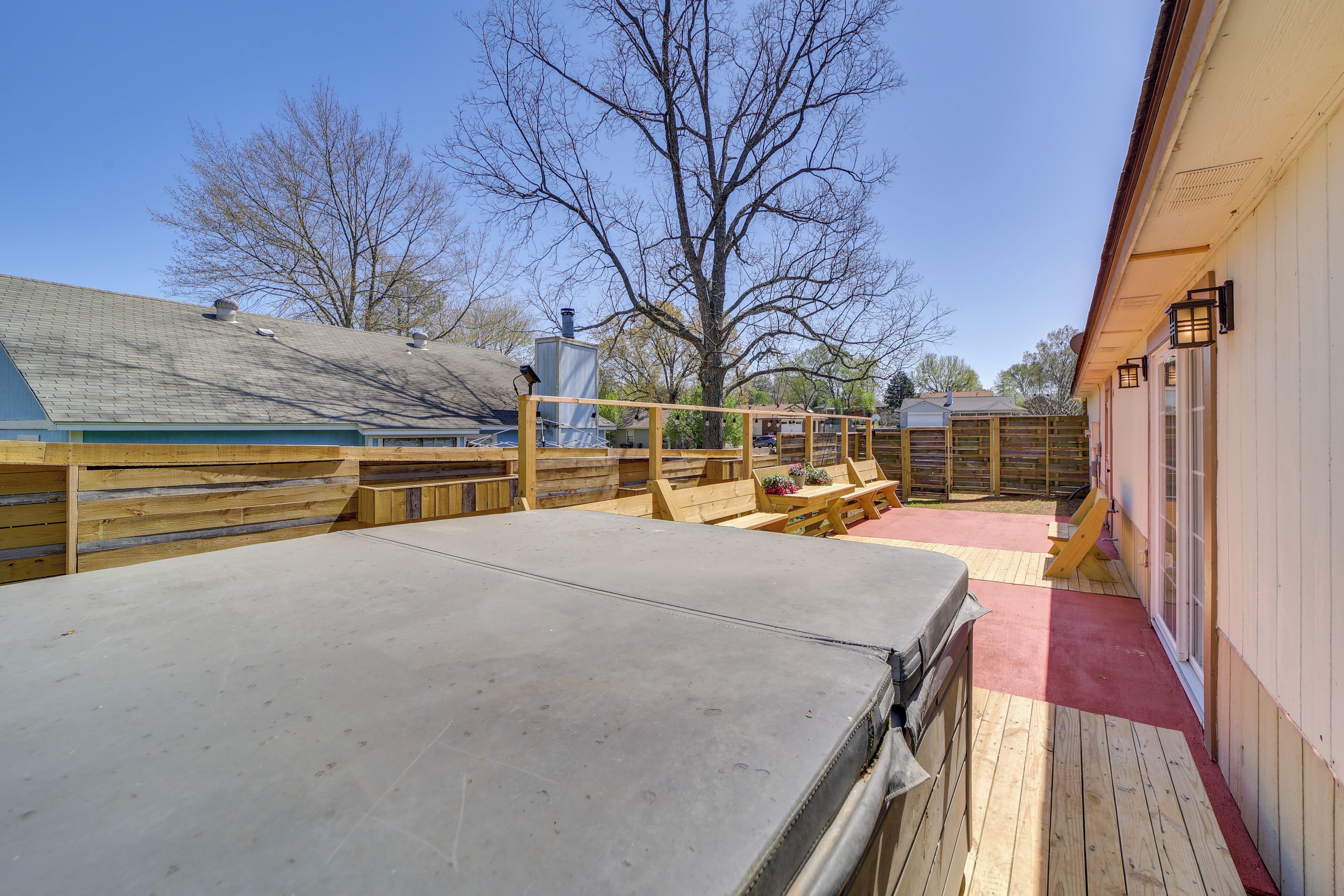 A wooden deck with a metal table, a wooden fence, and a building with a red roof.