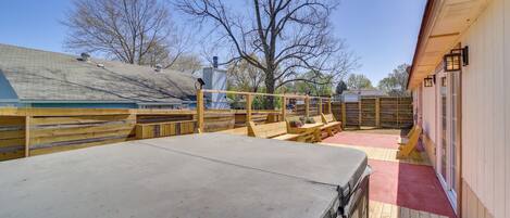 A wooden deck with a metal table, a wooden fence, and a building with a red roof.