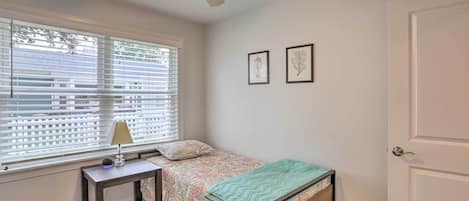 A bedroom with a bed, a nightstand, a lamp, a ceiling fan, and two framed pictures on the wall.