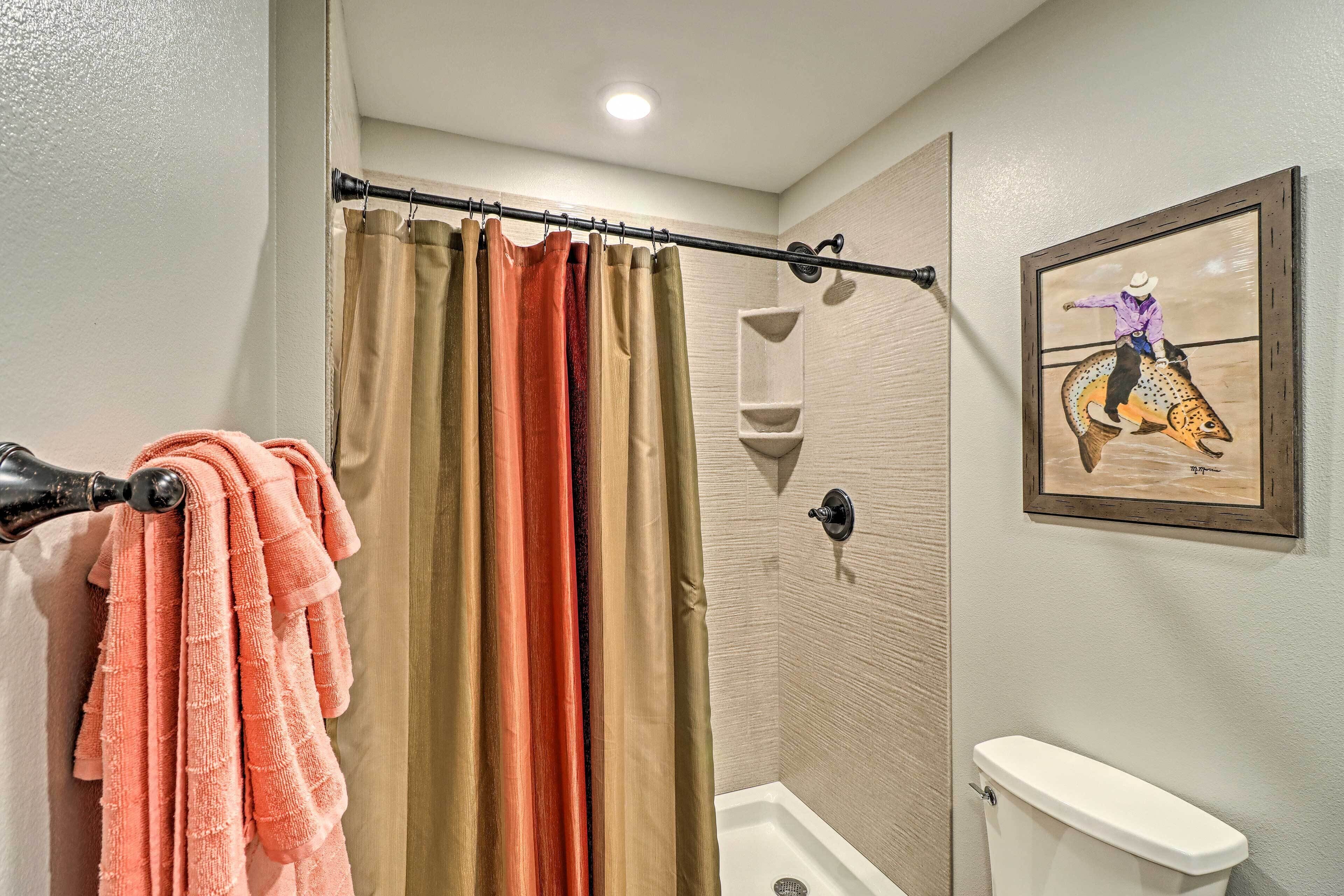 A bathroom with a shower curtain, a toilet, and a wall-mounted shelf.