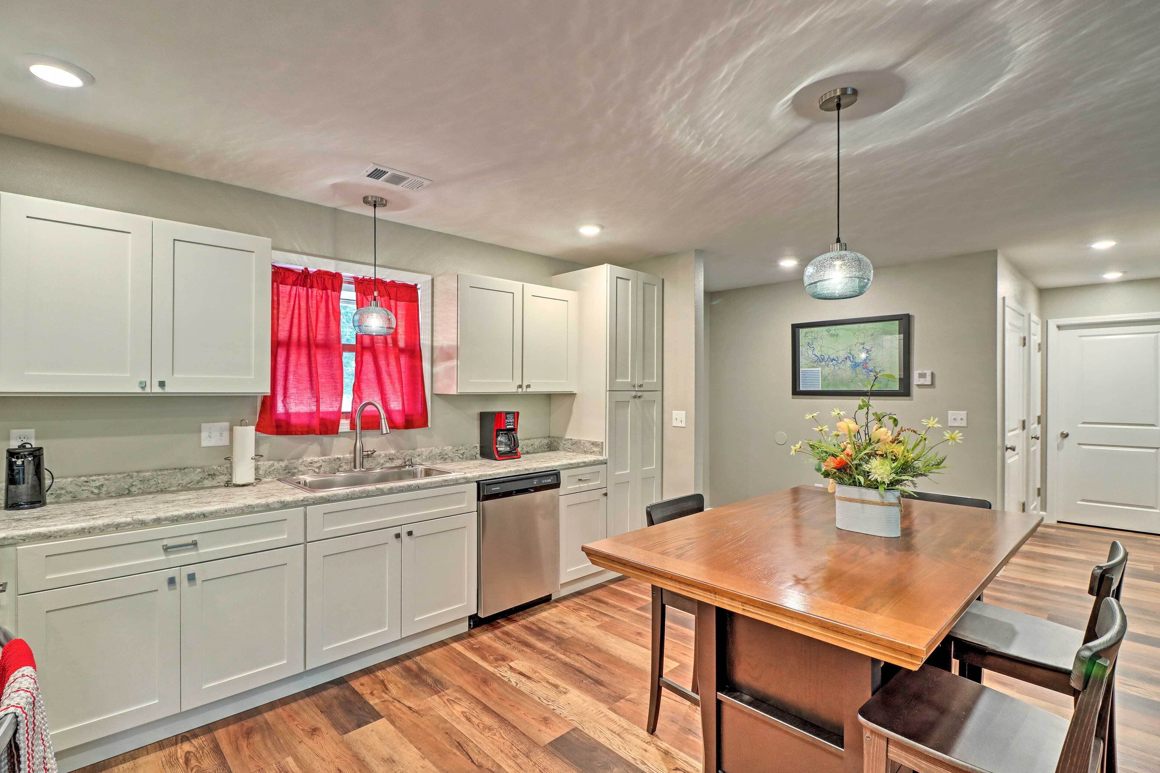 A modern kitchen with white cabinets, a wooden dining table, and a red curtain.
