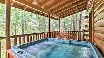 Relax in a hot tub on a shaded deck surrounded by a forest.