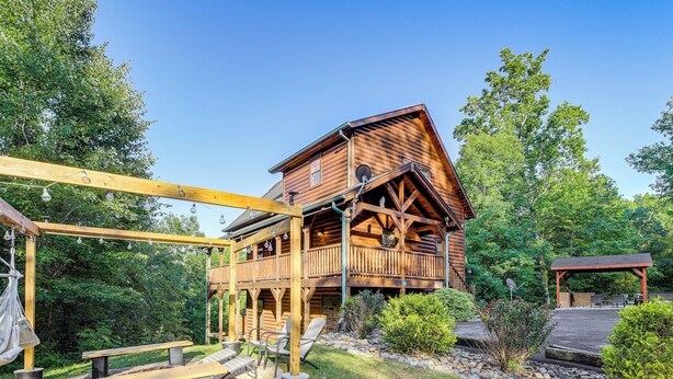 A wooden cabin with a balcony, outdoor seating, and a covered patio area.