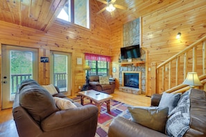 LâintĂ©rieur dâun chalet en bois, avec une cheminĂ©e, un tĂ©lĂ©viseur et un escalier.