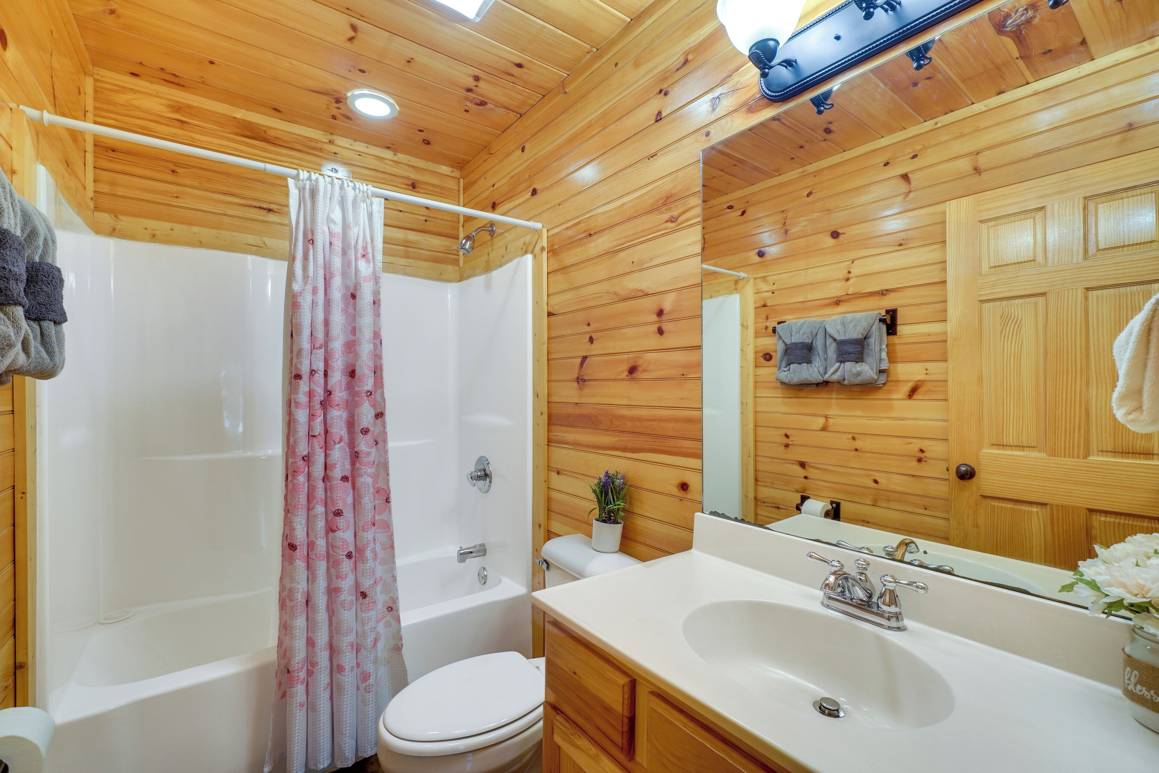 A wooden-paneled bathroom with a bathtub, toilet, and sink.