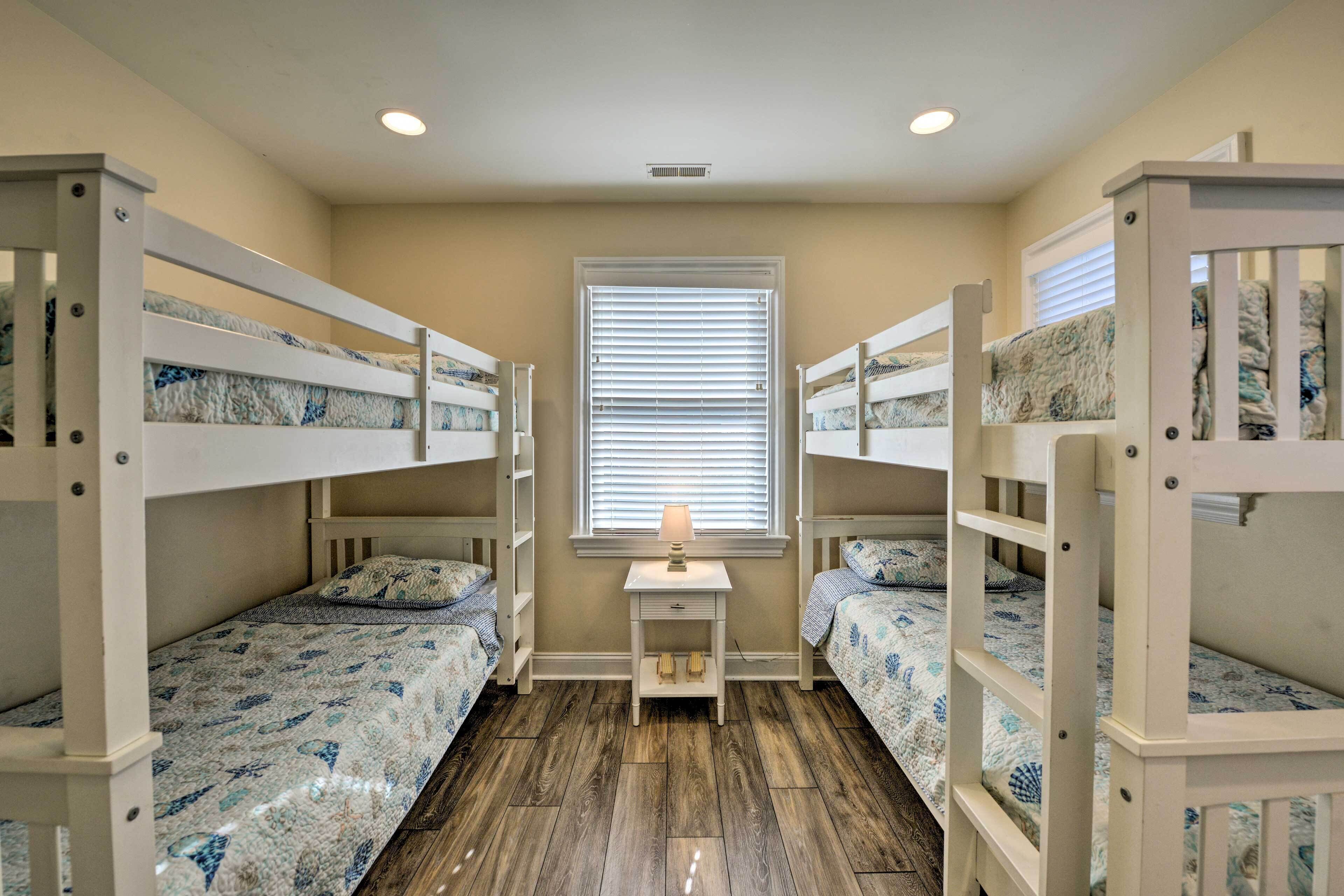 A room with bunk beds, a small desk, and a window with blinds.