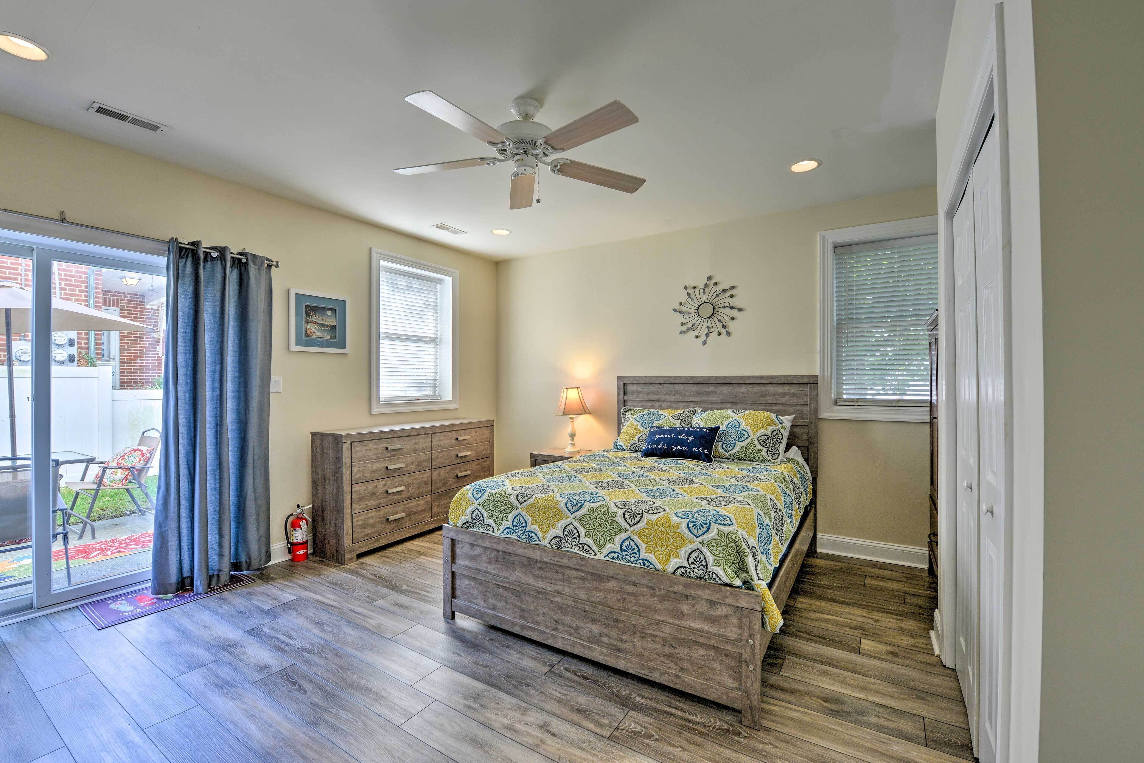 A bedroom with a bed, a ceiling fan, a nightstand, and a window with blinds.