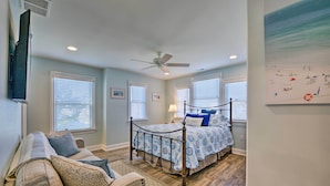A bedroom with a bed, a ceiling fan, a TV mounted on the wall, and a painting on the wall. - Wildwood Townhome w/ Patio: 1 Block To The Beach! (Wildwood)