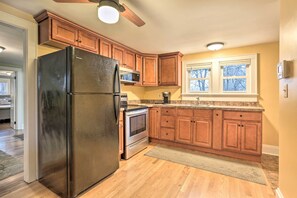 Una cocina con armarios de madera, un refrigerador de acero inoxidable, un horno integrado y un ventanal con vistas a árboles.
