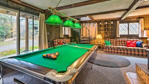 Ein Billardtisch in einem Raum mit einer Couch und einer Lampe.