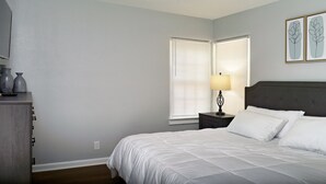 Una camera da letto con un letto, un comodino, una lampada e due quadri appesi al muro.