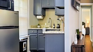 Una cucina moderna con mobili grigi, un frigorifero in acciaio inossidabile e un piano di lavoro con lavello e diversi elettrodomestici.