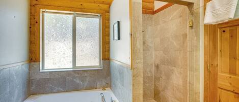 A bathroom with a bathtub, a shower, and a window.