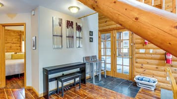 Interior de madera con escalera, zona de comedor y cama.