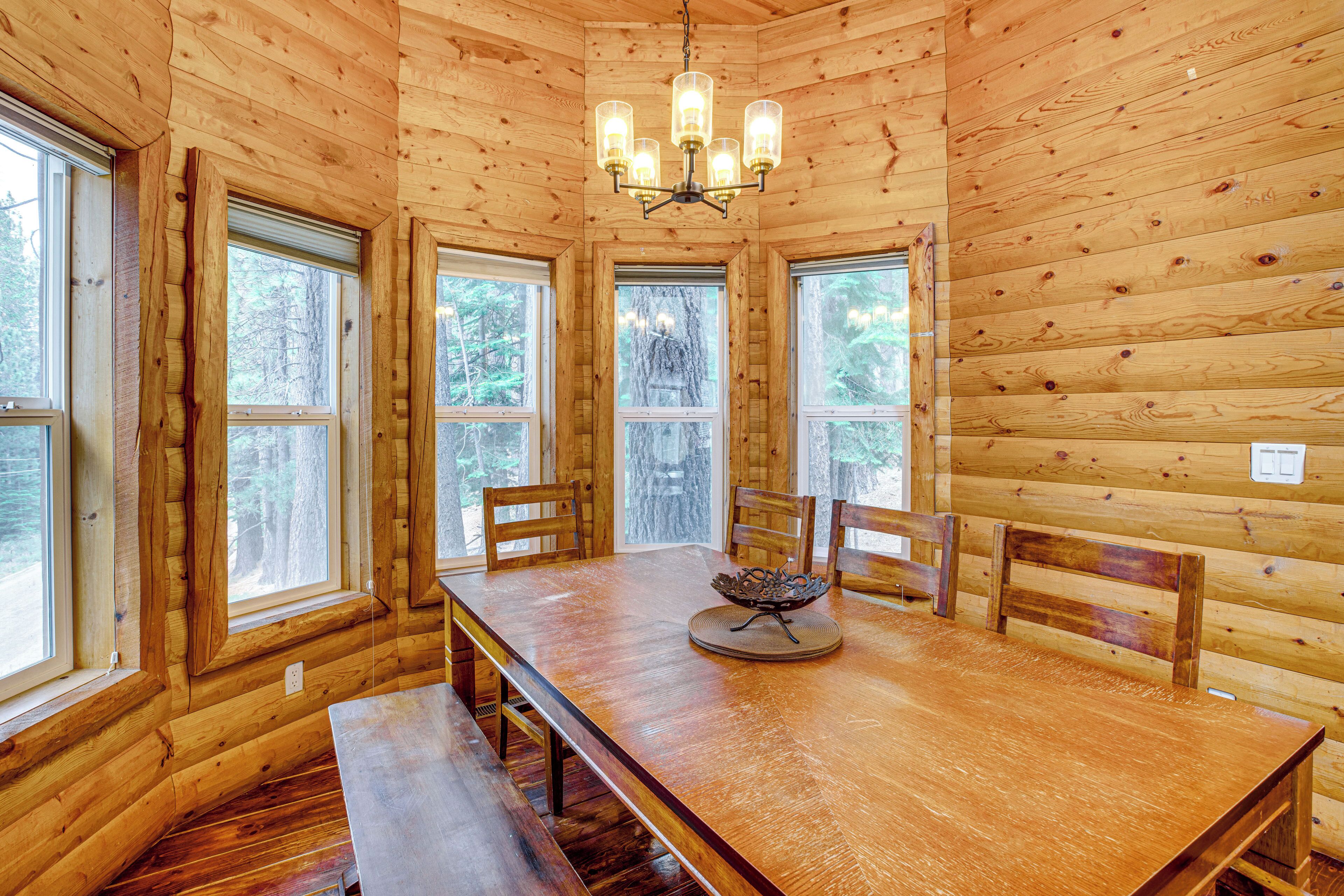 A wooden interior with a dining table, chairs, and a chandelier.