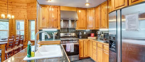 A kitchen with wooden cabinets, stainless steel appliances, granite countertops, and a dining area with wooden chairs and a table.
