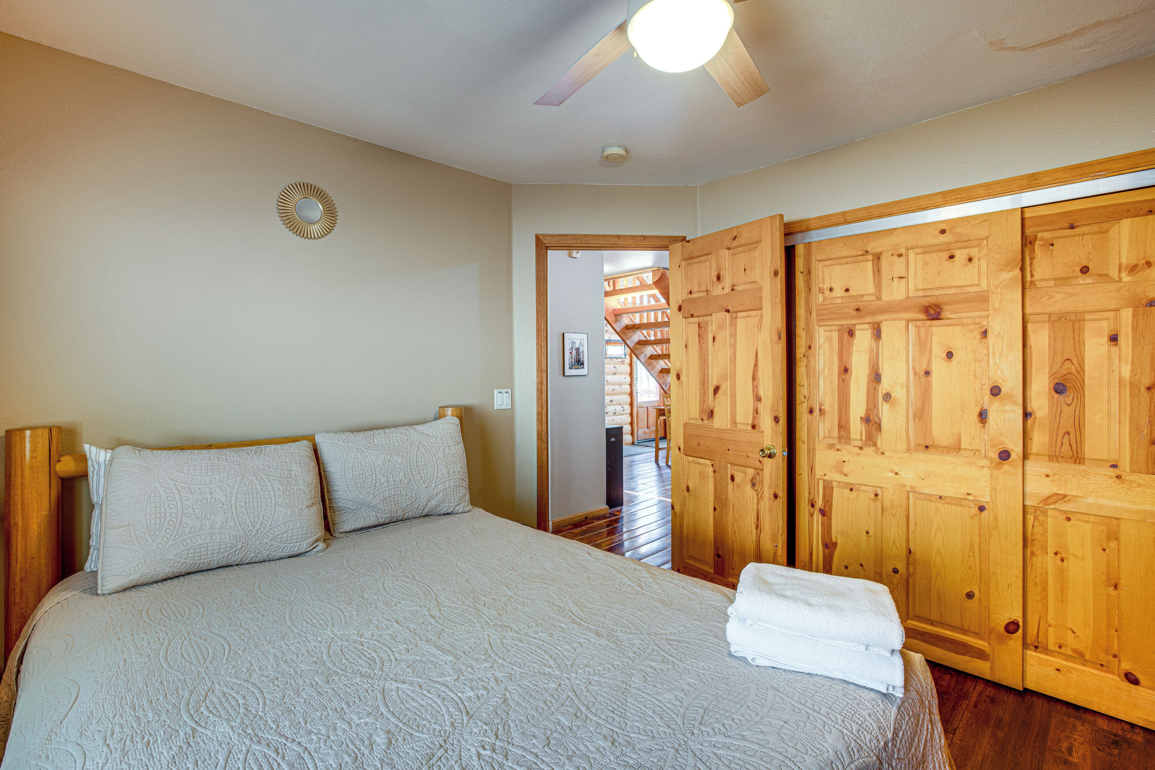 A bedroom with a bed, wooden wardrobe, and a ceiling fan.