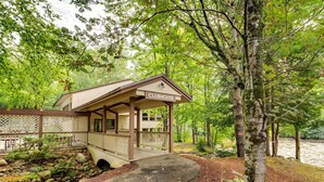 A clubhouse with a covered porch, surrounded by trees and a natural landscape.
