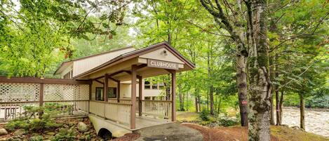 A clubhouse with a covered porch, surrounded by trees and a natural landscape.