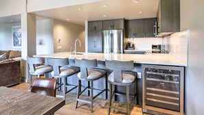A modern kitchen with a central island, bar stools, stainless steel appliances, and a built-in oven. - Tasteful Snowmass Escape < 1 Mi to Slopes! (Snowmass Village)