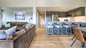 A modern living room with a sofa and a dining area with bar stools. - Tasteful Snowmass Escape < 1 Mi to Slopes! (Snowmass Village)