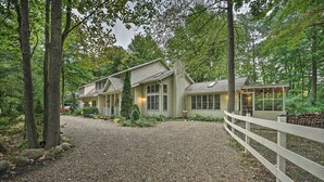 A house with a gravel driveway, surrounded by trees and a white fence. - Lakeside Escape Steps to Lake Michigan Beach! (Lakeside)