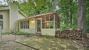 A house with a covered porch, a fire pit, and a stack of firewood. - Lakeside Escape Steps to Lake Michigan Beach! (Lakeside)