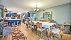 A spacious dining area with a long table, wooden chairs, and a chandelier. - Lakeside Escape Steps to Lake Michigan Beach! (Lakeside)