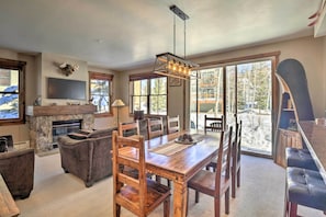 A spacious living room with a stone fireplace, wooden dining table, and comfortable seating. - Walk to Lifts: Breck Condo on Main St w/ Amenities (Breckenridge)