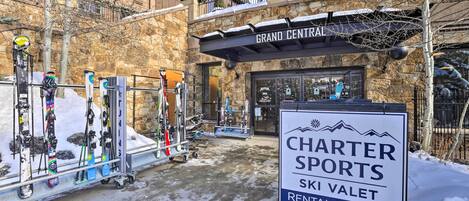 Tienda de alquiler de esquíes llamada Charter Sports, con un letrero, esquíes y tablas de snowboard a la vista.