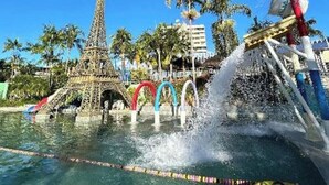 A water park with a replica of the Eiffel Tower, a water slide, and a pool with lane markers.
