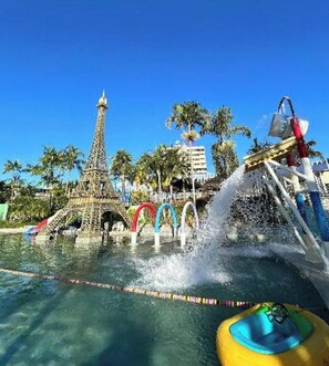Parque acuático con una réplica de la Torre Eiffel, un tobogán de agua y una piscina con carriles delimitados.