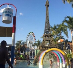 Un parc aquatique comprenant une réplique de la tour Eiffel, une grande roue et un toboggan aquatique aux couleurs vives.