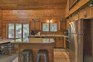 A wooden cabin kitchen with a central island, stainless steel refrigerator, and wooden cabinets. - Alluring Nisswa Cabin on Gull Lake w/ Fireplace! (Nisswa)