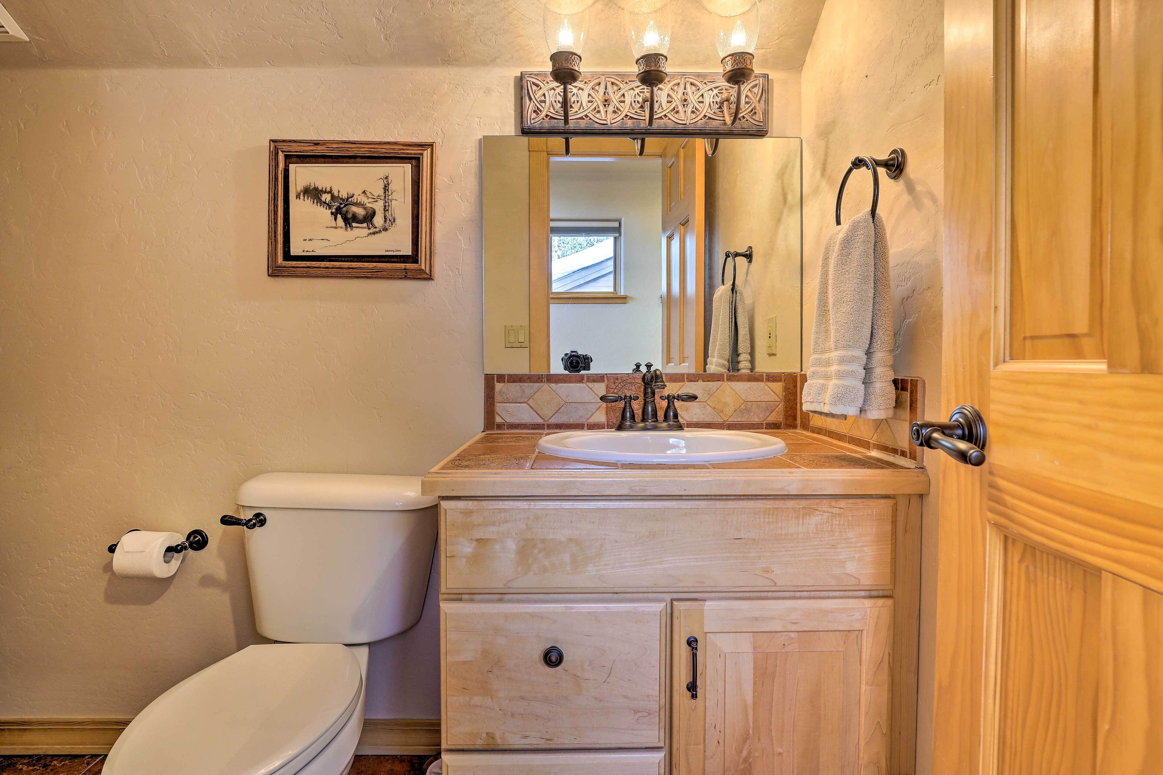 Een badkamer met toilet, wastafel, een wastafelmeubel met lades, een spiegel en een inlijsting foto aan de muur.