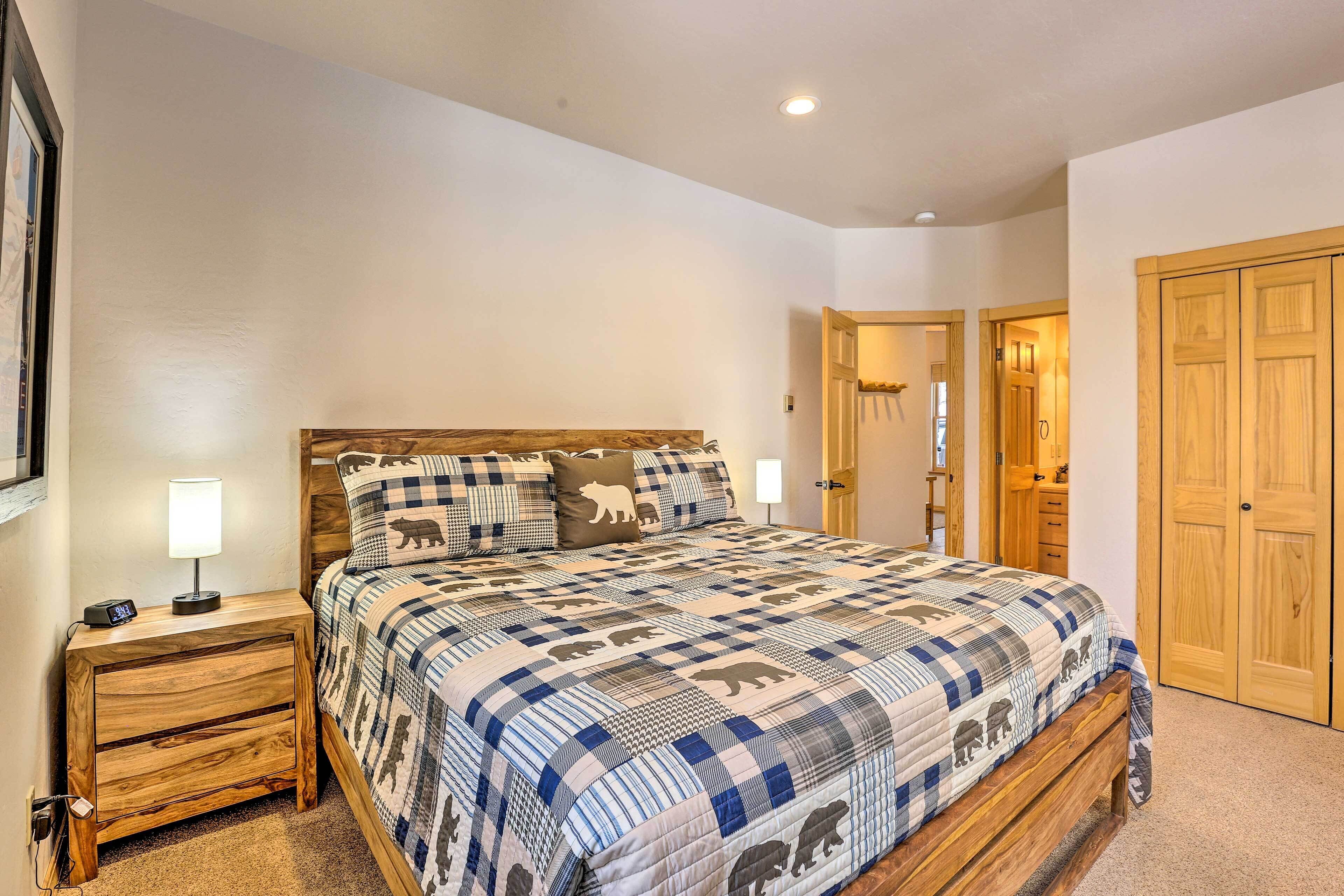 A bedroom with a large bed, wooden nightstands, a bedside table with a lamp, and a wardrobe.