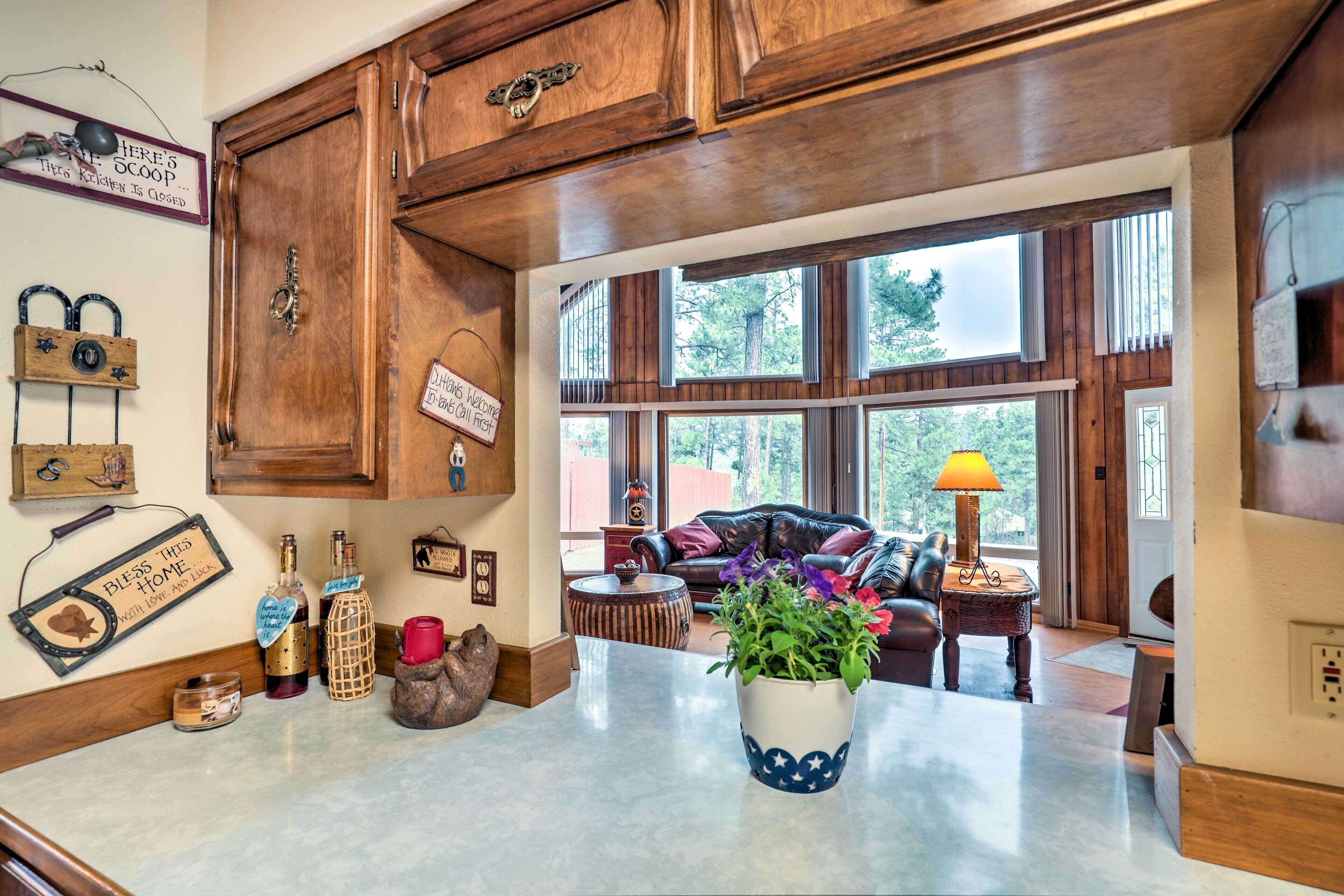 A kitchen with wooden cabinets, a marble countertop, and a potted plant.