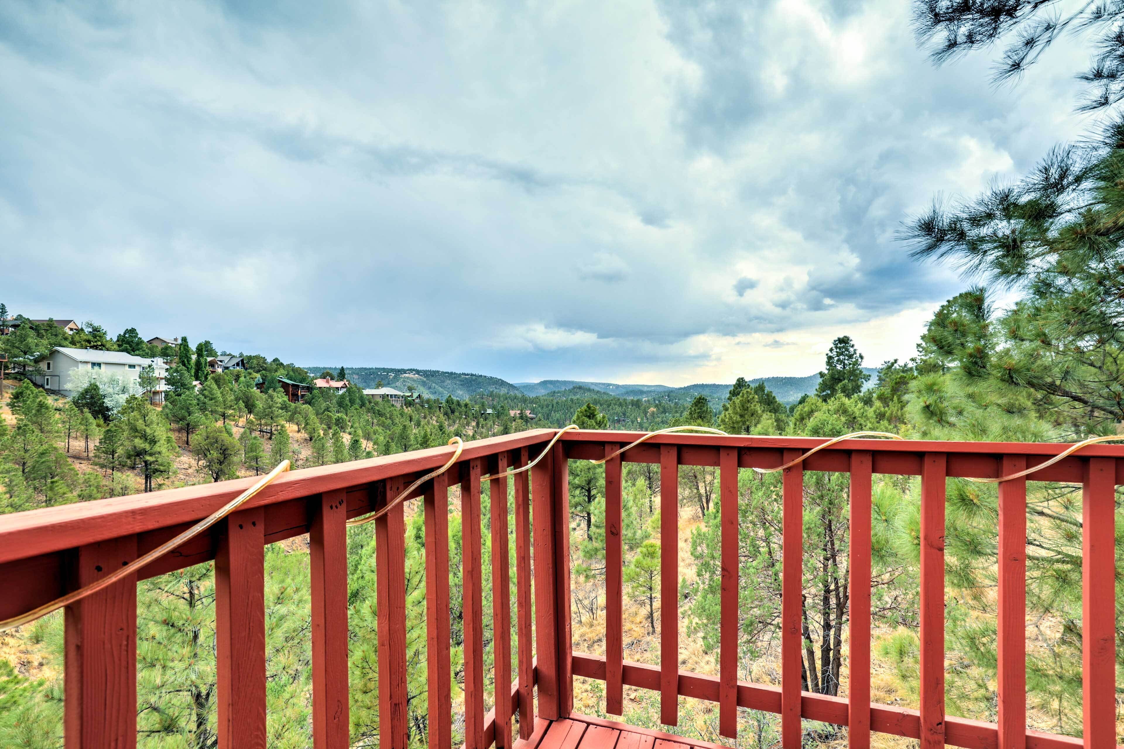 A wooden deck with a view of a mountainous landscape and scattered houses.