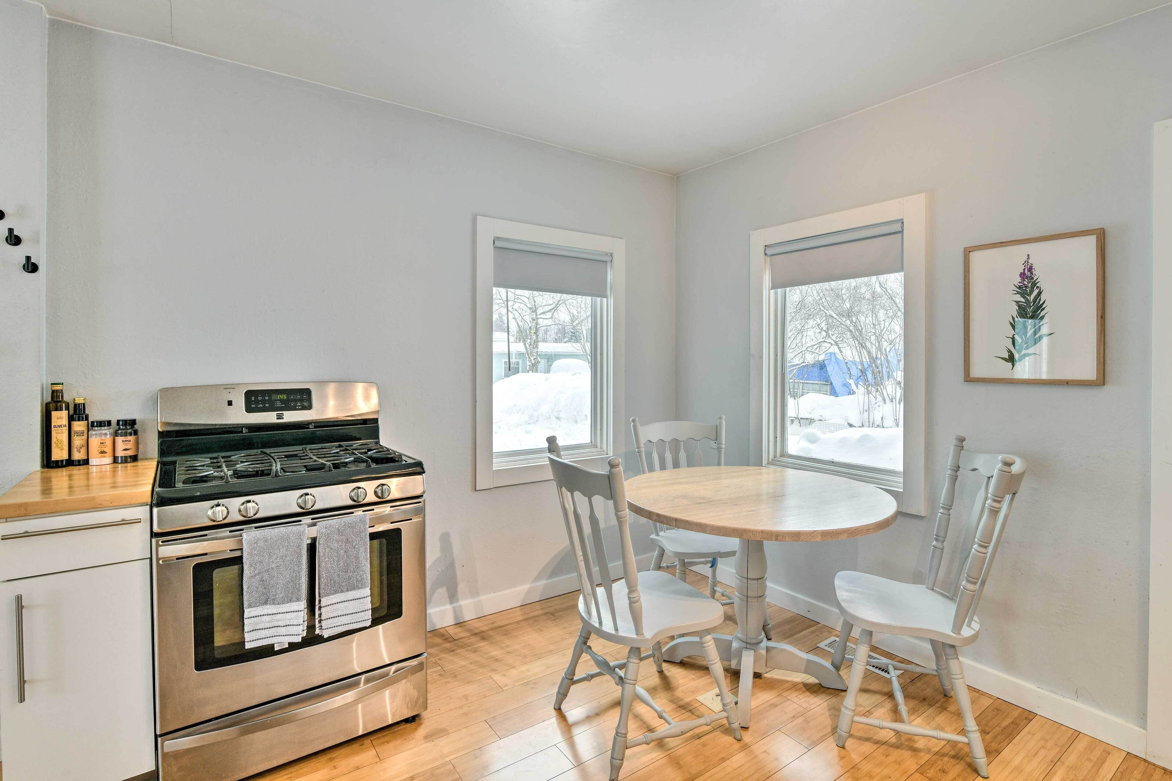 A kitchen with a stove, oven, and dining table with chairs.