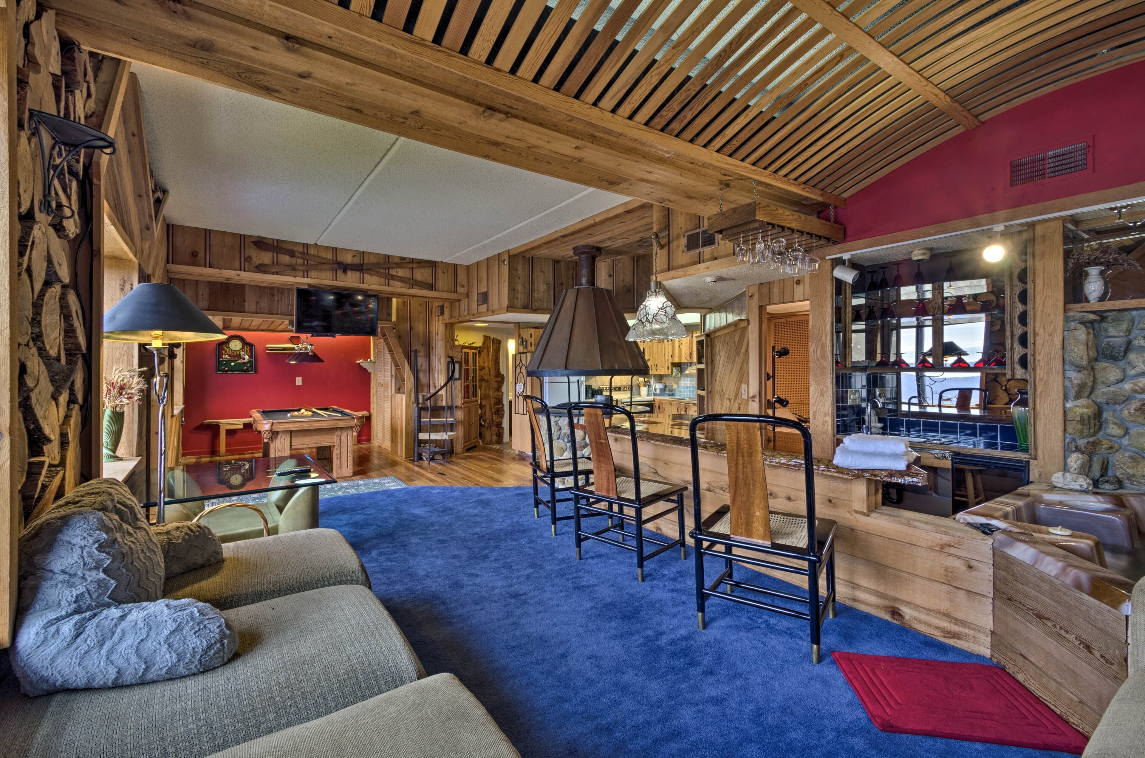 A rustic interior with wooden beams, a bar area, and a cozy seating area with a blue carpet.
