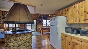 A rustic kitchen with wooden cabinets, a stone island, and a large chimney. - Sugar Mountain Resort Condo w/ Pool Table & Views! (Banner Elk)