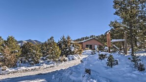Un paysage enneigé avec une maison, des arbres et une montagne en arrière-plan.