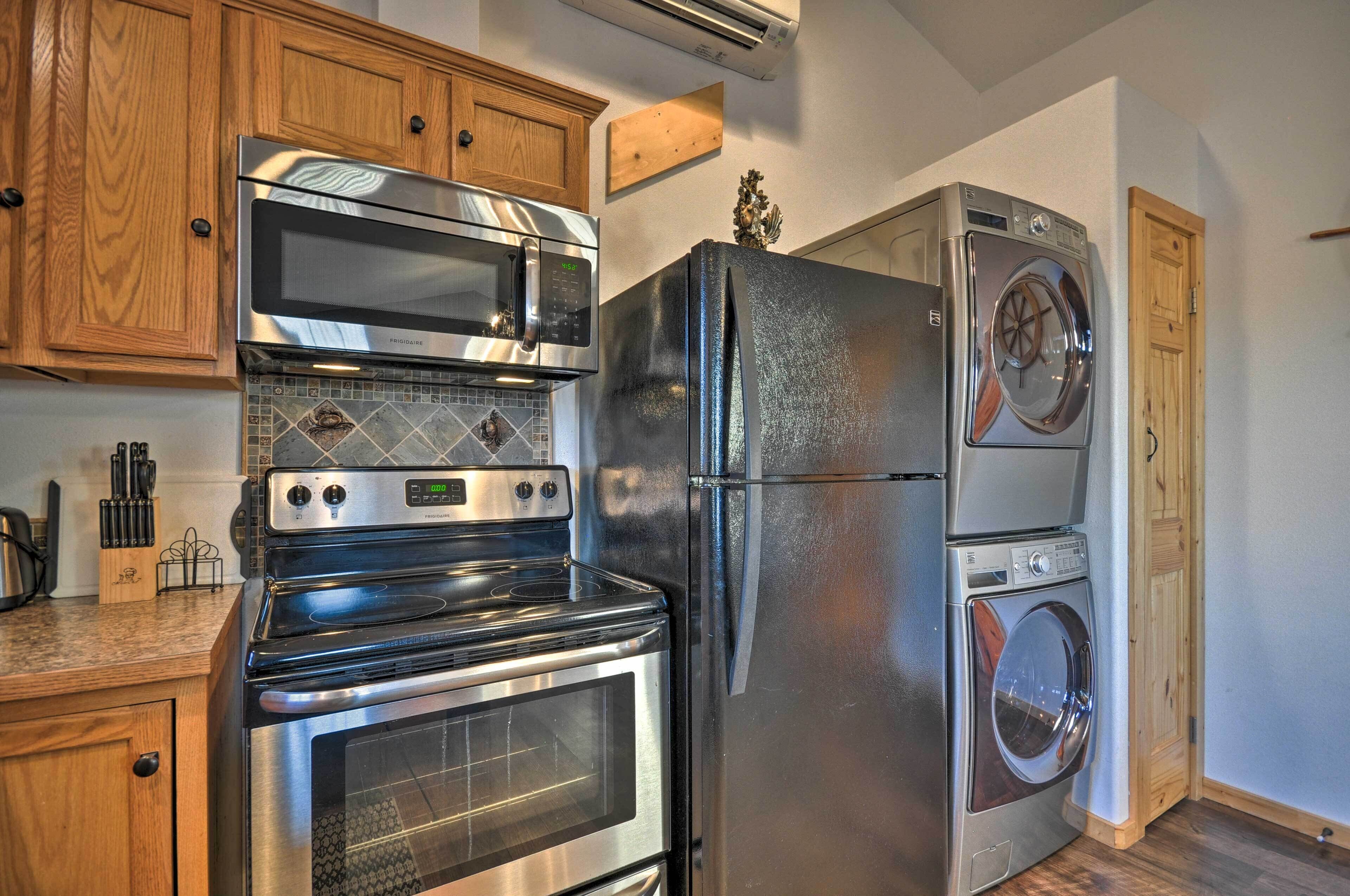 A kitchen with stainless steel appliances including a microwave, oven, refrigerator, and washing machine.