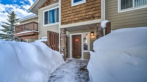 A two-story house with a snow-covered entrance and a wooden deck.