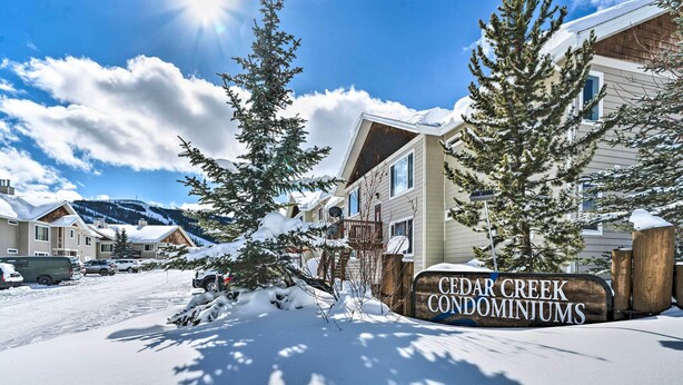 A snow-covered residential area with a sign for Cedar Creek Condominiums.
