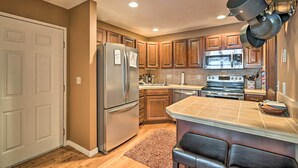 A kitchen with wooden cabinets, a stainless steel refrigerator, a microwave, and a stove.