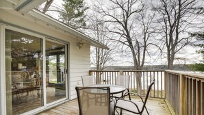 Une terrasse en bois avec une porte vitrée donnant sur un espace de vie.
