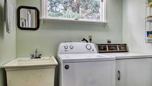 Une buanderie équipée d’un lave-linge, d’un évier et d’une fenêtre.